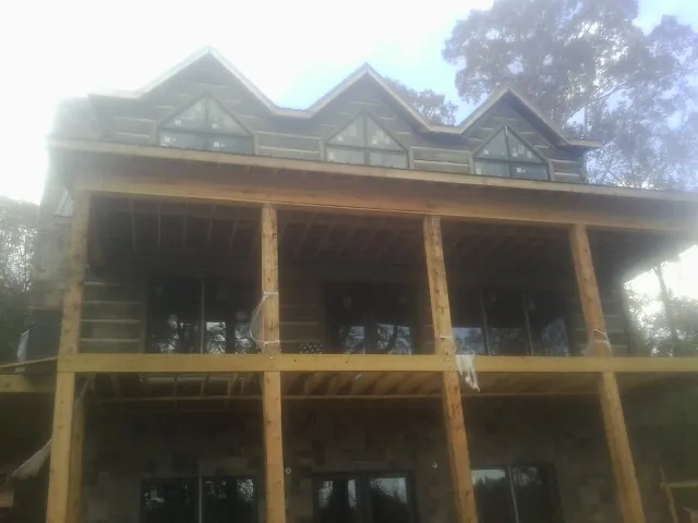 Dormers and porch framing on a large log home under construction — Roof Coating work by our crew in Montezuma