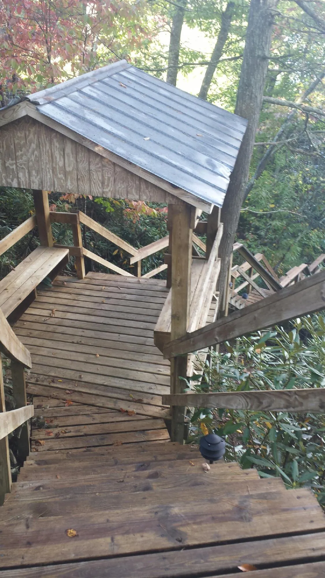 Metal roofed shelter over wooden steps on a wooded walkway — Skylight Repair & Installation work by our crew in Montezuma